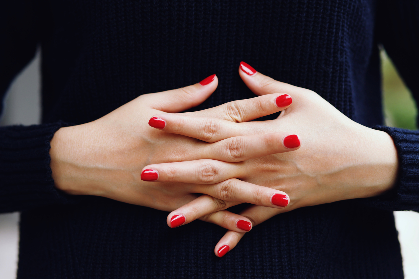 Beautiful female finger nails with red nail closeup on petals.
